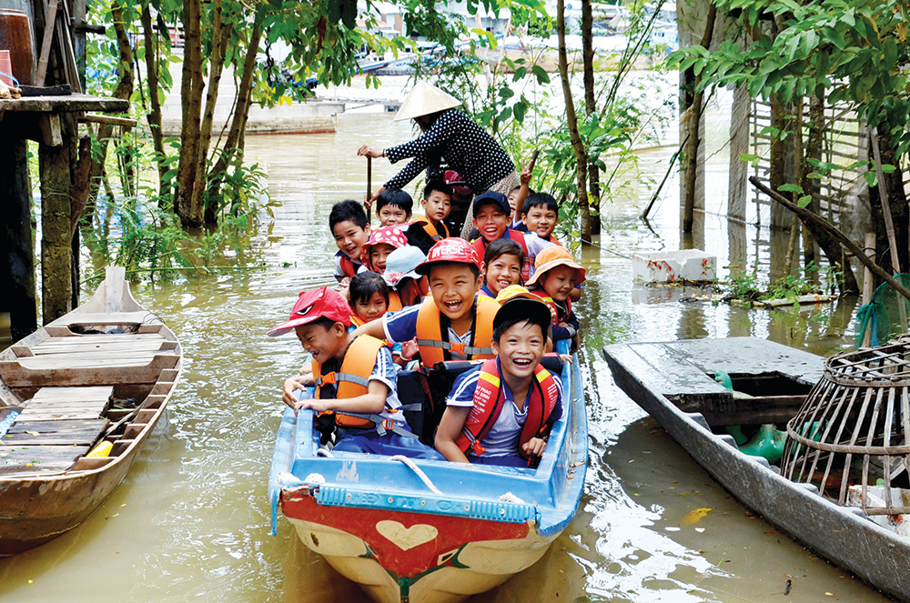 Đưa trẻ đến trường an toàn trong mùa lũ ở huyện đầu nguồn An Phú.    