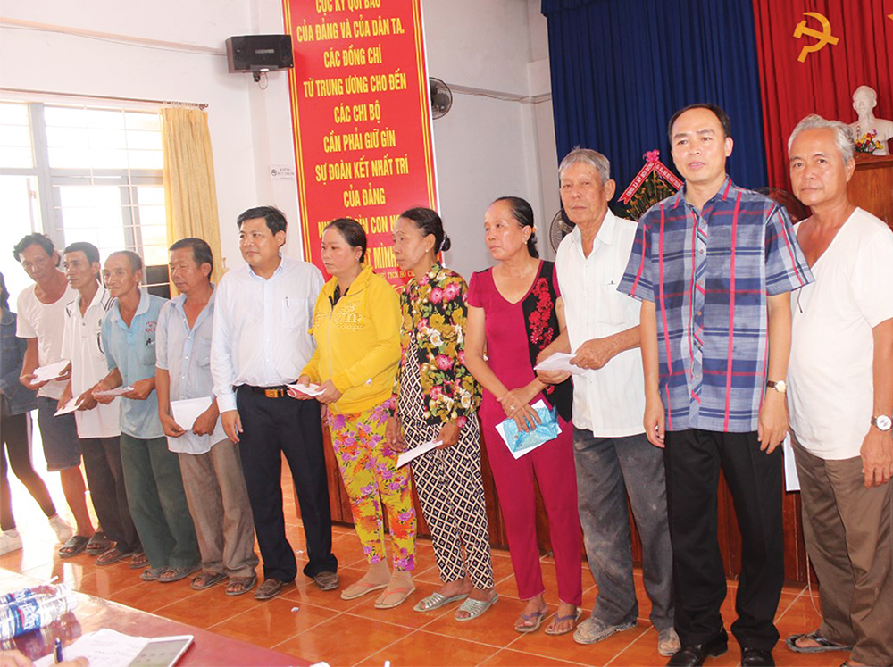 Phó Chủ tịch UBND tỉnh Lâm Quang Thi (thứ hai, bên phải) trao tiền hỗ trợ cho các hộ dân bị sạt lở